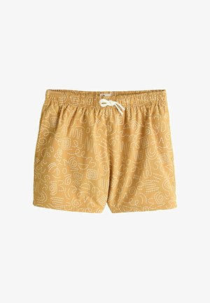 Pantaloni de baie galben muștar cu modele abstracte în linii albe și șnur alb la talia elastică pe un fundal alb.