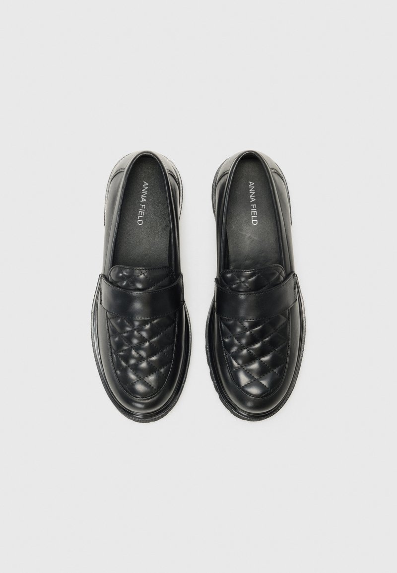 Schwarze Loafers mit einem gesteppten Muster an der Zehe, glatten Lederelementen und einer gepolsterten Sohle für Komfort. Markenlogo sichtbar im Inneren.