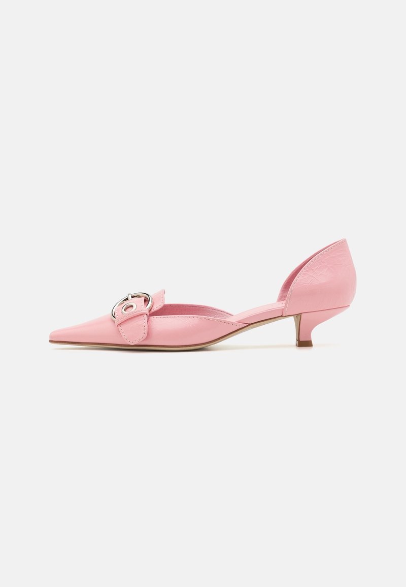 Chaussure rose à bout pointu, talon bas, avec une bride à boucle argentée et un détail découpé sur le côté, sur fond blanc.