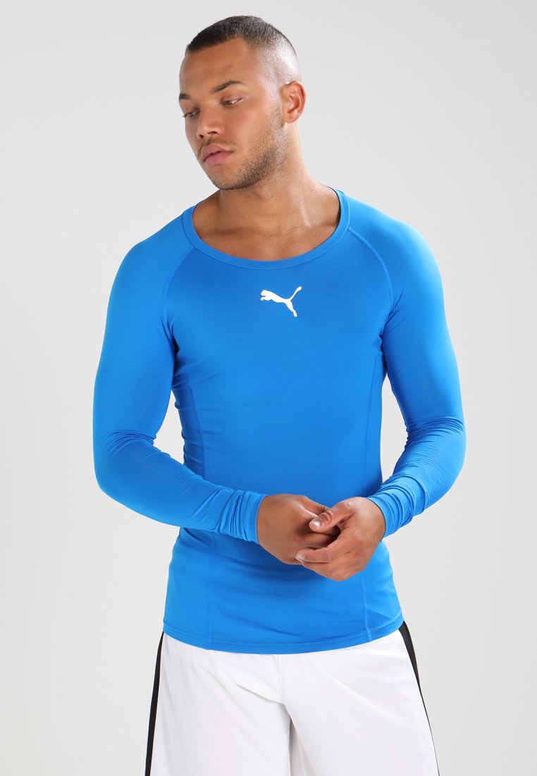 Maglietta sportiva a maniche lunghe di colore blu brillante, realizzata in tessuto liscio e elasticizzato. Presenta un collo rotondo e un logo bianco sul petto.