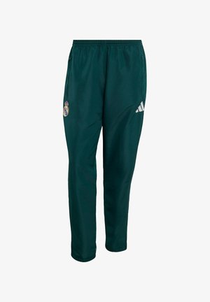 Ciemnozielone spodnie sportowe z logo Realu Madryt na lewej udzie i białym logo Adidas na prawej, elastycznym pasem i kieszeniami po bokach.