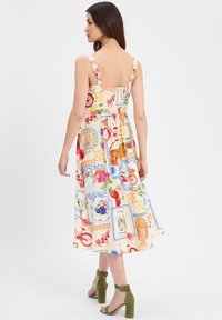 Floral-patterned, sleeveless dress with a fitted bodice and flowing skirt. Features vibrant colors: orange, pink, green, and blue.