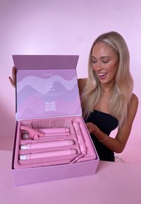 Różowy zestaw prostownicy w różowym pudełku z przegródkami. Zawiera kilka wymiennych wałków oraz rękawicę odporną na ciepło.