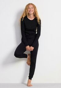 Set da loungewear in cotone nero con maniche lunghe e pantaloni in stile jogger. Caratterizzato da un collo rotondo, dettagli con bottoni e vita regolabile con cordoncino.