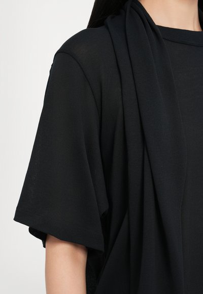 Top nero a maglia con maniche corte e scollatura drappeggiata. Il tessuto sembra morbido con una leggera texture.