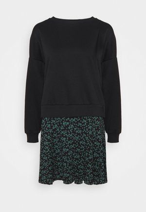 Sort langærmet sweatshirt kombineret med en sort nederdel med et lille grønt blomsterprint.