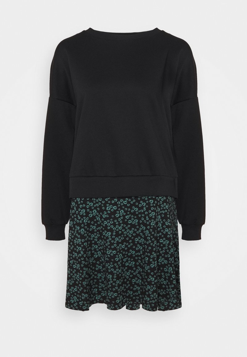 Sweat-shirt noir à manches longues associé à une jupe noire avec un petit motif floral vert.