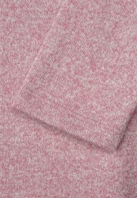 Knitted fabric in light pink with a textured pattern. The close-up shows a soft, woven surface with variations in pink tones.