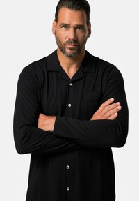 Black long-sleeve button-up shirt with a collar, featuring a pocket and two buttons at the front, made of a smooth, lightweight fabric.