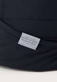 Dark blue fabric patch with stitched edges, featuring a label that reads "KEEPING THE GREAT OUTDOORS GREAT" in gray text.