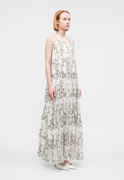 Robe longue et fluide en tissu léger et transparent avec un motif floral et des volants en étages. Couleur blanc cassé avec des accents verts.