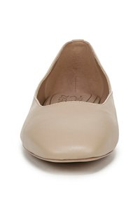 Scarpa piatta beige con punta affusolata, esterno in pelle liscia, design minimalista e taglio basso attorno alla caviglia. L'interno è foderato con un materiale morbido.