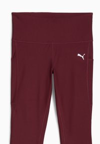Burgundowe legginsy sportowe z szerokim pasem i bocznymi kieszeniami. Wykonane z elastycznego materiału, z białym logo po lewej stronie.