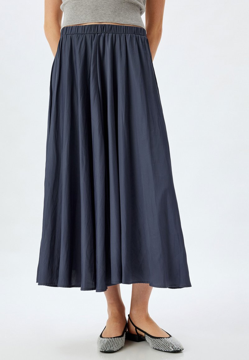 Jupe longue bleu marine en tissu léger avec une taille élastique, présentant un design fluide et une texture douce.