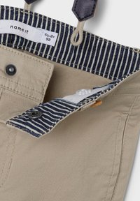 Pantaloni di cotone beige con vita a righe blu, dotati di chiusura a bottone e dettagli di cucitura. L'etichetta indica la taglia 1½-2 anni.