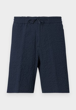 Βερμούδα από υφή ύφασμα σε ναυτικό μπλε με ελαστική μέση και δέσιμο μπροστά, μέχρι το γόνατο, casual στυλ.