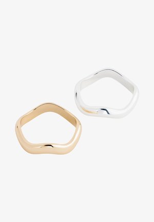 Two irregular pentagon-shaped rings, one in gold and one in silver, displayed on a white background.