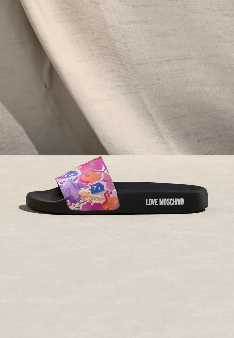 Black slide sandal with a colorful floral strap and "Love Moschino" logo on the sole's side and strap, placed on a light surface.