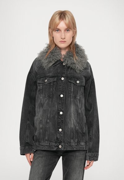 Veste en jean noir avec un col en fourrure, ornée de boutons en métal argenté, deux poches poitrine et une coupe décontractée. Le tissu a une texture usée.