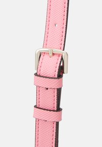 Sangle synthétique rose avec une surface texturée, boucle en métal argenté et bords noirs contrastés ; comprend plusieurs trous d'ajustement.