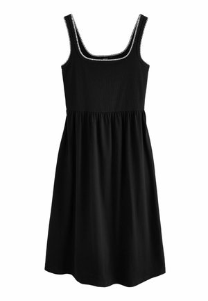 Robe noire sans manches jusqu'aux genoux avec un bord zigzag blanc le long de l'encolure carrée et des bretelles, taille froncée et tissu doux.
