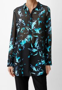 Chemisier noir en voile avec un motif floral abstrait bleu, devant à boutons, manches longues et col. Coupe ample et ourlet arrondi.