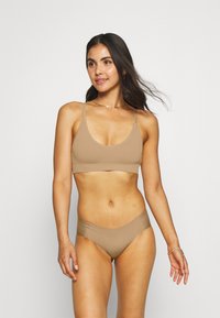 Tan ribbed bikini set featuring a scoop neck bralette and mid-rise bottom. Smooth texture with thin straps and seamless edges.