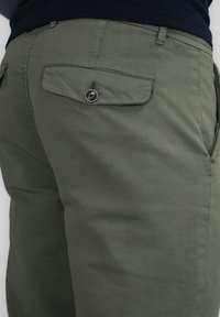 Olive green cotton trousers with a smooth texture, featuring a buttoned back pocket and side pockets for functionality.