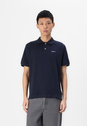 Marineblå polo-shirt i bomull, med klassisk krage, knapplåda med två knappar och broderad logotyp på vänster sida. Korta ärmar och rak skärning.