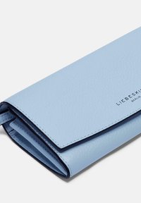 Jasnoniebieski skórzany portfel, fakturowana powierzchnia, składana konstrukcja, wewnętrzna ciemnoniebieska wyściółka, wytłoczone logo w czerni.