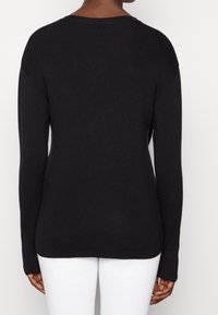 Schwarzer Strickpullover mit langen Ärmeln, geripptem Muster und lockerer Passform. Verfügt über einen runden Ausschnitt und keine sichtbaren Verschlüsse.