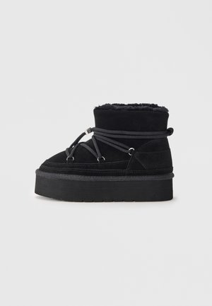 Black suede ankle boots with a plush lining, rounded toe, and thick sole. Features a gray lace system with metallic accents.