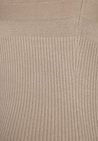 Tessuto a maglia a coste beige con una texture liscia, caratterizzato da linee verticali e una leggera lucentezza. Il materiale ha una qualità morbida e stretchy.