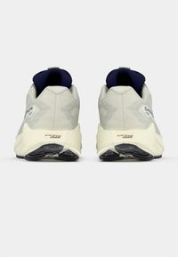 Vaaleanharmaat urheilukengät, joissa on tekstuuripinta, laivastonsiniset yksityiskohdat ja pehmustettu pohja, jossa on musta kumipinta pitävyyttä varten.