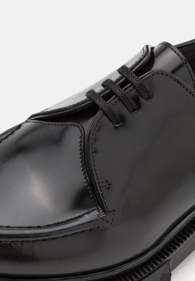 Schwarzer, polierter Lederschuh mit abgerundeter Spitze, klassischem Schnürdesign, strukturiertem Obermaterial und kontrastierenden Nähten.