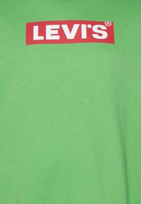 Grøn bomulds t-shirt med et stort rødt Levi's-logo med hvid tekst centreret på forsiden. Blød tekstur og afslappet pasform.