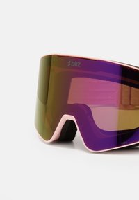 Lyžařské brýle s růžovým rámem a velkým fialovým sklem, se soft black pásem pro bezpečné uchycení a reflexní úpravou pro snížení oslnění.