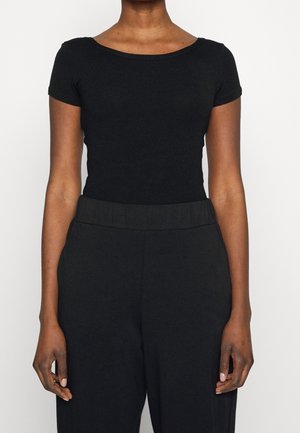 Haut noir à manches courtes avec un col rond, fabriqué en tissu extensible. Associé à un pantalon noir taille haute, doté d'une taille élastique.