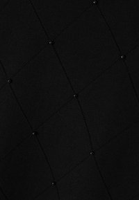 Schwarzer Strickstoff mit einem Rautenmuster, das kleine schwarze Perlen an den Schnittpunkten aufweist und ein strukturiertes Aussehen schafft.