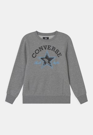 Sudadera gris de mezcla de algodón, con un gran gráfico de estrella azul y texto negro "CONVERSE Chuck Taylor" encima de la estrella. Puños acanalados.