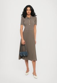 Ribbed midi-mekko taupe-värissä, jossa on lyhyet hihat, nappilista ja laskostettu hame. Yhdistetty pieneen siniseen käsilaukkuun ja valkoisiin kenkiin.