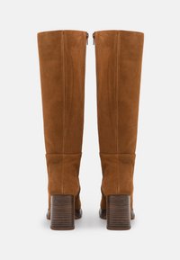 Stivali al ginocchio in suede marrone con tacco a blocco cilindrico, caratterizzati da una chiusura con zip e un design con cima piegata, texture liscia e linee pulite.