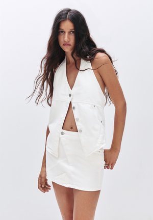 Haut sans manches blanc avec un décolleté en V et une fermeture à boutons, associé à une jupe évasée assortie présentant des coutures structurées et des détails minimalistes.