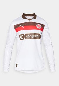Hvit langermet fotballdrakt med brun krage, som har røde og brune horisontale striper, et Puma-logo, og et "congstar" sponsorlogo.