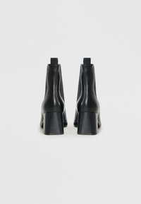 Sorte lær ankle boots med en glat overflade, rund tå og en chunky, ribbet hæl. Har en pull-tab bagpå for nem påtagning.