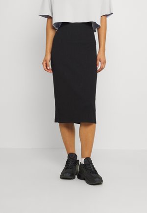 Czarna, prążkowana spódnica midi o prostym kroju, zestawiona z czarnymi trampkami. Góra w jasnoszarym kolorze, luźna, z krótkimi rękawami.