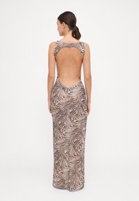 Vista posteriore di un vestito aderente senza maniche, caratterizzato da un motivo a zebra ondulato nei toni del beige e del marrone, con una profonda scollatura aperta sul retro.