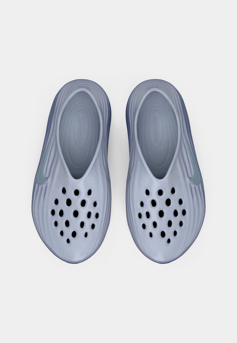Par de zapatillas azules sin cordones con múltiples agujeros de ventilación en la parte superior y el logo de Nike en cada lado, vistas desde arriba.