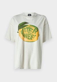Camiseta de algodón gris claro con un gran gráfico de limón amarillo y texto verde que dice "AMARGO DULCE" con un acento de hoja verde.