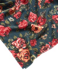 Tela de color verde azulado oscuro con patrones de rosas en rojo, amarillo y rosa, ligeramente arrugada, mostrando un diseño floral detallado y variaciones de color.
